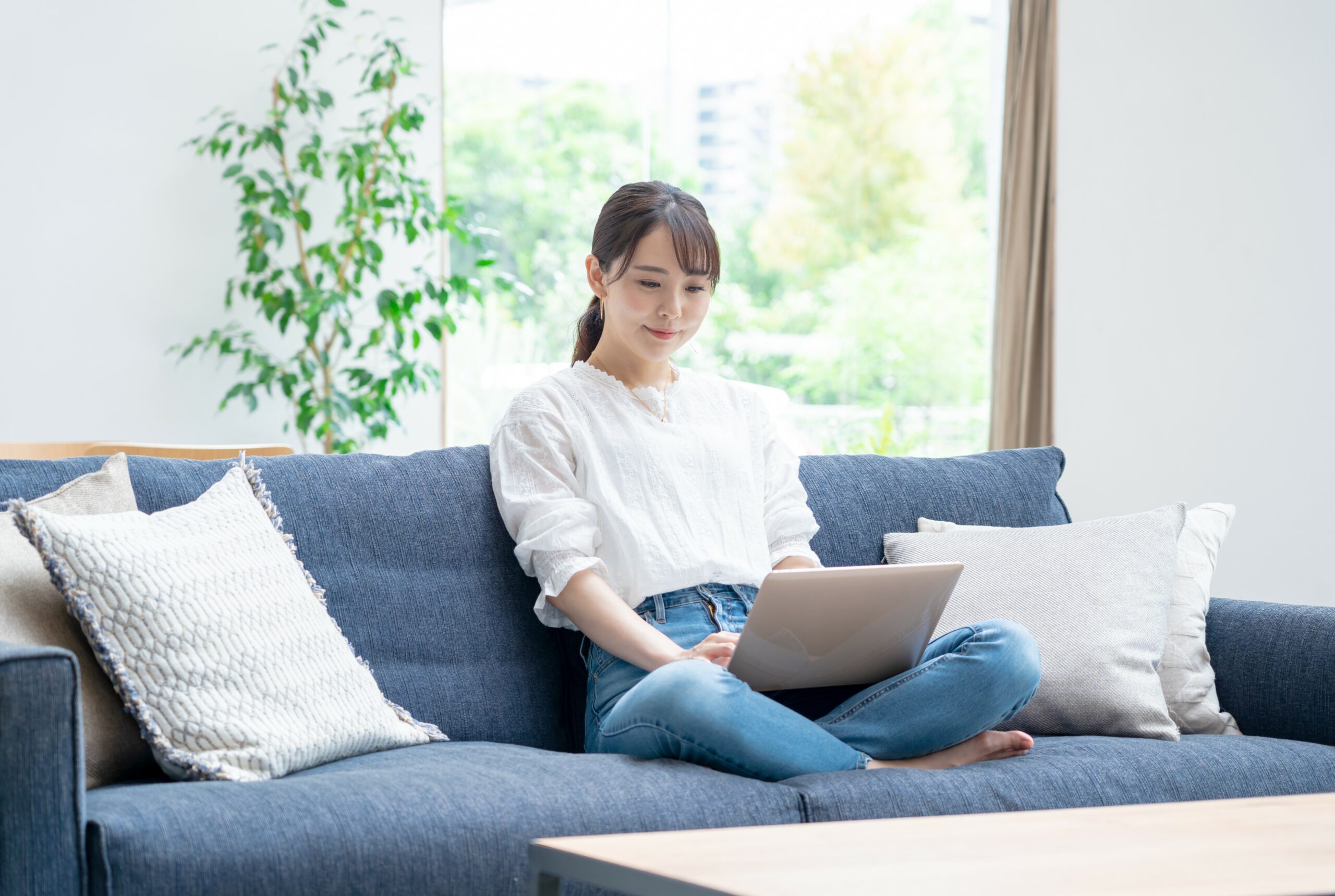 ソファに座って在宅ワークをする主婦